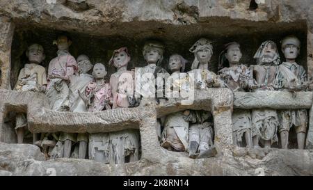 Tau tau o effigi di legno del defunto che custodisce le loro tombe costruito nella scogliera nel villaggio tradizionale di Suaya, Tana Toraja, Sulawesi del Sud, Indonesia Foto Stock