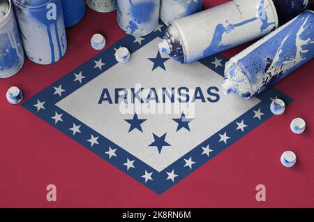 Arkansas bandiera di stato degli Stati Uniti e pochi bombolette spray usate per la pittura graffiti. Concetto di cultura Street art, problemi di vandalismo Foto Stock