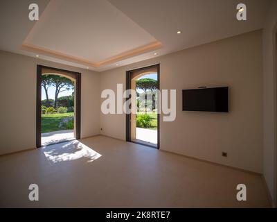 Camera spaziosa con due finestre che si aprono sul lussuoso giardino e TV a parete Foto Stock