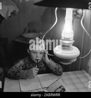 Aurskog 11 febbraio 1956 'questi bambini hanno 3 miglia di strada scolastica' i bambini Kjell da Nybak, Hallvard da Sinkerud e Marit da Stenshaugen devono camminare per 6 km da soli attraverso la foresta nera di notte prima di raggiungere il bus scolastico a Bekesaga. Devono alzarsi alle ore 5 per raggiungere l'autobus che va alla scuola di Haneborg ad Aurskog. A Kjell in Nybak, hanno ancora lampade di paraffina. Qui si siede e fa i compiti. Foto; Sverre A. Børretzen / corrente / NTB Foto Stock