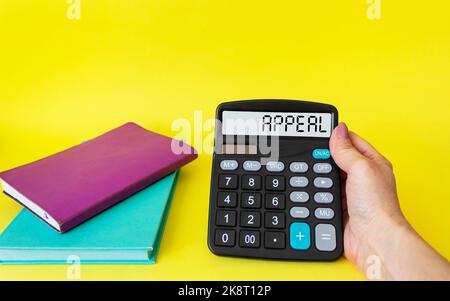 Testo DI APPELLO scritto sul display di una calcolatrice in mano femminile, su sfondo giallo con diari Foto Stock