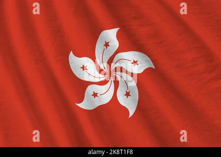 Bandiera di Hong kong con grandi pieghe che sventolano da vicino sotto la luce dello studio in interni. I simboli e i colori ufficiali in tessuto banner Foto Stock