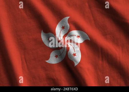 Bandiera di Hong kong con grandi pieghe che sventolano da vicino sotto la luce dello studio in interni. I simboli e i colori ufficiali in tessuto banner Foto Stock