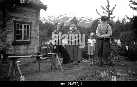 Norvegia, estate 1943 vita quotidiana durante la guerra. I permessi di viaggio erano difficili da raggiungere durante la seconda guerra mondiale, motivo per cui molti hanno scelto le biciclette e si sono concentrati sulle soste nelle fattorie lungo il tragitto. Qui la città incontra il villaggio: Giovane donna della città in giacca e pantaloni moderni con coppie sposate più anziane in abiti tradizionali in una piccola fattoria di montagna. Bambina nella foto anche. Foto: NTB Foto Stock