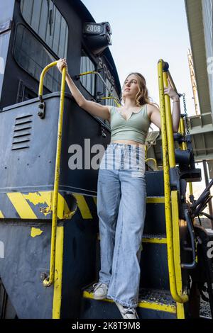 Giovane donna in piedi sulle scale di un motore elettrico diesel treno Foto Stock