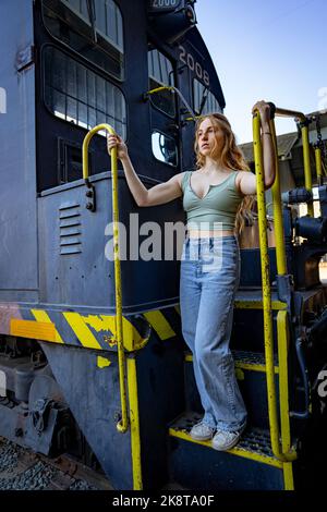 Giovane donna in piedi sulle scale di un motore elettrico diesel treno Foto Stock