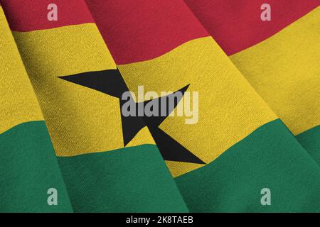 Bandiera del Ghana con grandi pieghe che sventolano da vicino sotto la luce dello studio in interni. I simboli e i colori ufficiali in tessuto banner Foto Stock