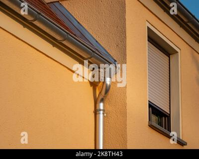 WASP nido su un edificio esterno. Il nido grigio è appeso accanto alla grondaia del tetto di una casa residenziale. Distruggere la casa di insetto è pericoloso. Foto Stock