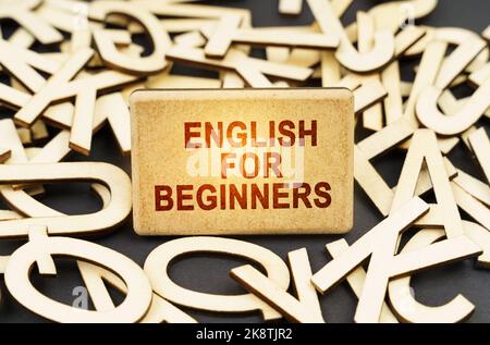 Concetto di istruzione. Tra le lettere di legno c'è un segno con l'iscrizione - inglese per principianti Foto Stock