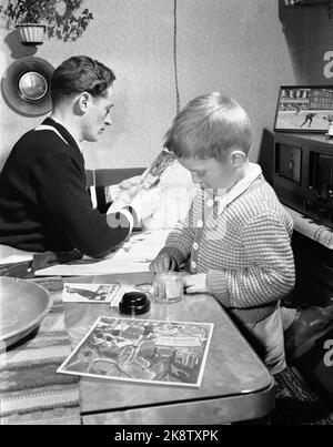 Trondheim 19500204. Stella del pattinaggio Hjalmar Andersen 'Hjallis' (27 anni) a casa con la sua famiglia a Trondheim. Il tempo rimasto dopo il lavoro di camionista e lo sport ha avuto il suo proprio. Qui, Jan Erik aiuta il padre a tenere aggiornato il libro della scogliera. Hjalmar Andersen non solo forbice i suoi trionfi. Sono incluse anche le società di Clubmers. Foto: Sverre A. Børresen corrente / NTB Foto Stock