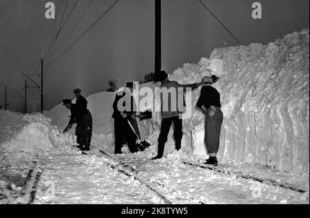 Nelaug stazione 19510207: Forte nevicata sulla parte meridionale del paese ha creato caos nel traffico ferroviario. In totale, cinque treni sono rimasti bloccati nelle masse di neve alle stazioni di Helldalsmo e Nelaug, e i passeggeri hanno dovuto trascorrere la notte in treni ghiacciati. Qui ci sono molte persone che lavorano con la neve di gulling alla stazione di Nerlaug. Foto: NTB / NTB Foto Stock