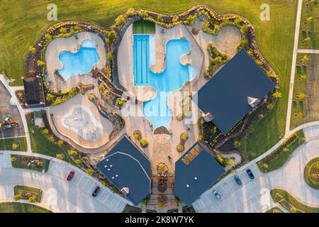 Ripresa aerea di prato verde, piscina, zona lounge vicino a bella villa nel cortile in estate. Foto Stock