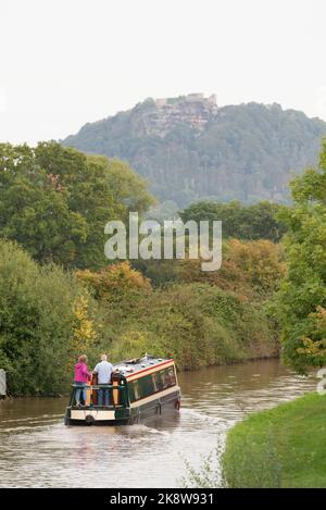 Narrowboaters navigando nel canale Shropshire Union in autunno in vista delle Crags Rocky del Castello di Beeston a Cheshire Foto Stock