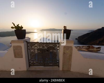Vista su Firostefani al tramonto sulla Caldera. Isole Cicladi greche di Santorini nel Mar Egeo. Vasi di fiori con cactus in primo piano Foto Stock