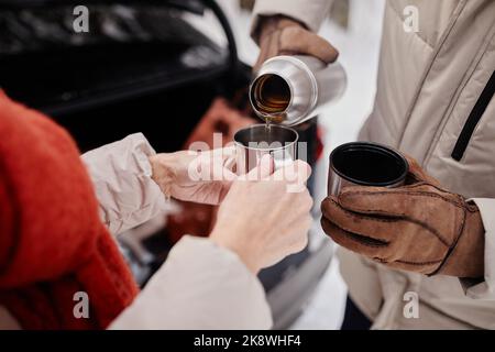 Primo piano di una coppia matura irriconoscibile che si gode una tazza di cocco caldo all'aperto in inverno Foto Stock