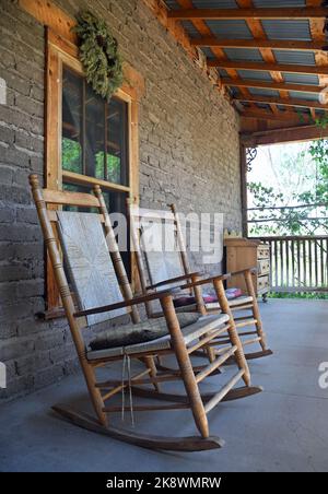 Antica sedia a dondolo in legno sul portico della fattoria Foto Stock