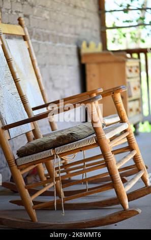 Antica sedia a dondolo in legno sul portico della fattoria Foto Stock