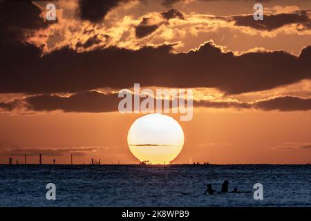 Incredibile tramonto sulla spiaggia di Waikiki con silhouette di barca a vela. Navigazione al tramonto alle Hawaii. Foto Stock