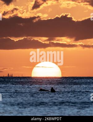 Incredibile tramonto sulla spiaggia di Waikiki con silhouette di barca a vela. Navigazione al tramonto alle Hawaii. Foto Stock