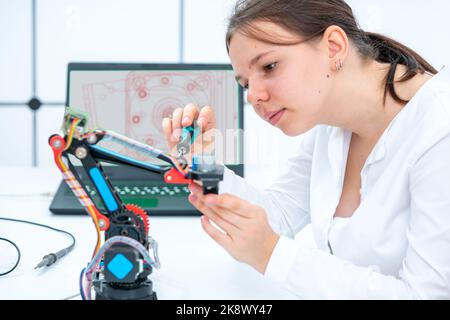 studentessa scolastica regola il modello di braccio robot industriale Foto Stock