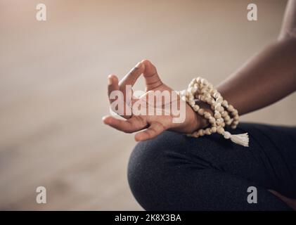 La pace viene dall'interno. Una donna irriconoscibile seduta in casa da sola e meditante con la mano in una mudra gyan. Foto Stock