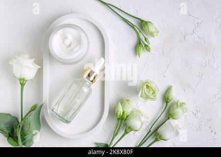 Bottiglie senza marchio in stile mockup. Sfondo di bellezza con prodotti cosmetici per il viso. Vaso aperto con crema viso e flacone contagocce con siero di bellezza su c Foto Stock