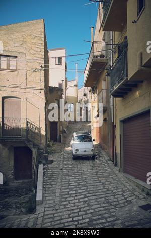 Auto vecchia Fiat 500 in una strada stretta del villaggio di Prizzi nella Sicilia Occidentale, Italia Foto Stock