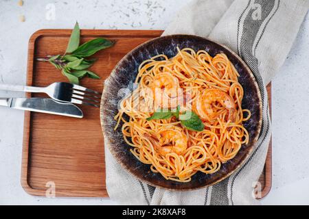 Vista dall'alto della pasta d'arancia con gamberi e salsa in un piatto su un tavolo. Foto Stock