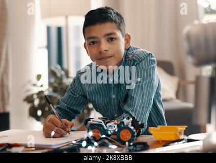 Im che lavora per diventare un ingegnere quando sono cresciuto. Ritratto di un bel ragazzo che fa i compiti sulla robotica a casa. Foto Stock