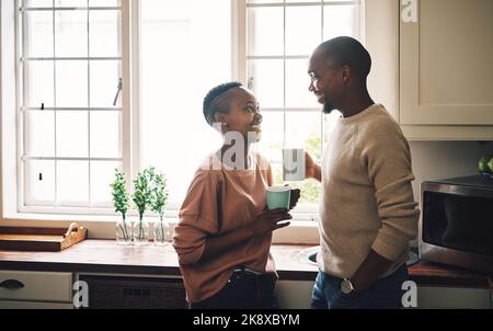 Tutto ciò di cui avete bisogno è amore e caffeina. Una giovane coppia felice che beve caffè e che trascorre il tempo insieme a casa. Foto Stock