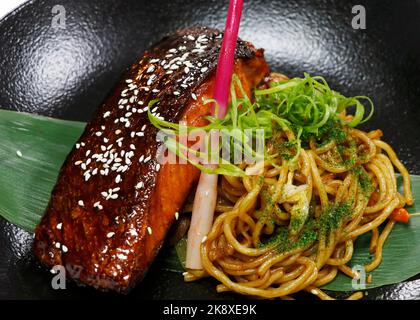 salmone giapponese teriyaki con spaghetti fritti e zenzero sparare in un recipiente nero con primo piano Foto Stock
