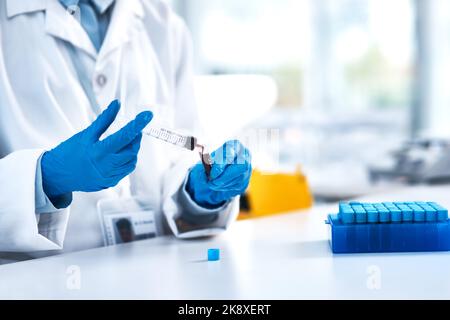 Questo esempio è stato appena presentato per il test. Primo piano di uno scienziato irriconoscibile che usa una siringa mentre lavora in laboratorio. Foto Stock