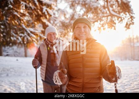 Vita in su ritratto di coppia matura sorridente godendo Nordic Walk nella foresta invernale al tramonto Foto Stock