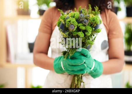 Pronto per il ritiro. Una giovane e irriconoscibile botanica femminile che tiene un bouquet di fiori mentre lavora nel suo fiorista. Foto Stock