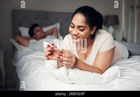 Gli piace quando indossi il rosso. Una bella giovane donna che applica lo smalto alle unghie. Foto Stock