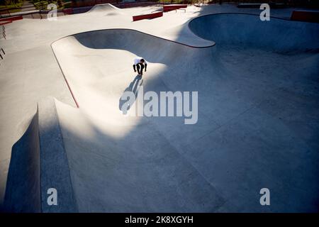 Vista aerea dell'uomo, skater a rotelle maschio su rollerblade allenamenti al moderno skate Park, all'aperto. Azione, movimento, abilità e sfide. Fare di diverso Foto Stock