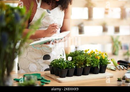 Questi stanno crescendo piacevolmente. Una giovane botanica femminile irriconoscibile che fa le note mentre lavora nel suo fiorista. Foto Stock