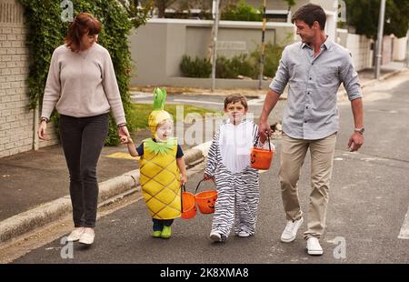 Trucco o trattare con i nostri piccoli mostri. Un'immagine completa di un adorabile trucco di famiglia o di un trattamento insieme nel quartiere di Halloween. Foto Stock