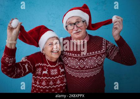 Ritratto di felice coppia anziana con cappelli di Babbo Natale in studio. Foto Stock