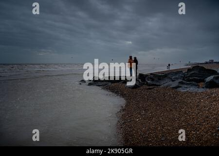 Coppia che guarda fuori al mare su un giorno di inverni freddi e blustery costa sud dell'Inghilterra Foto Stock