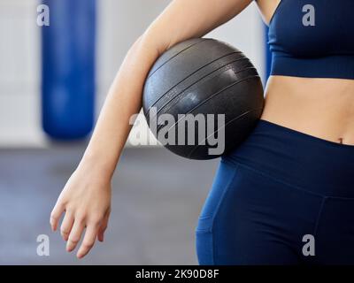 Fitness, esercizio fisico e donna con palla medica in una palestra di salute e benessere per l'allenamento o l'esercizio di peso. Braccio atleta femminile con attrezzatura da allenamento Foto Stock