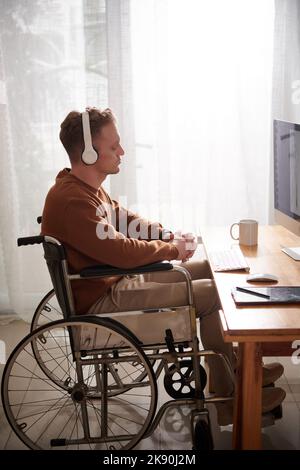 Giovane uomo penoso con disabilità che ascolta il msuic quando pensa alla nuova collezione di bozzetti di moda Foto Stock