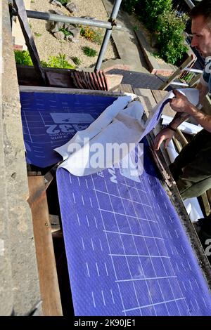 Lavori di copertura su tetto residenziale in tegole di argilla a baia hipped, montaggio membrana di sfiato Foto Stock