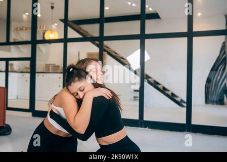 Due amiche si abbracciano dopo lo yoga Foto Stock
