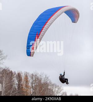 Skydiving sport estremi - paracadutista con paracadute dispiegato. Lo sportivo che vola su un parapendio. Bellissimo parapendio in volo su un dorso leggero Foto Stock