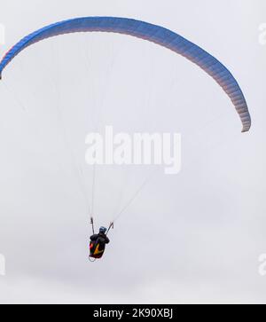 Skydiving sport estremi - paracadutista con paracadute dispiegato. Lo sportivo che vola su un parapendio. Bellissimo parapendio in volo su un dorso leggero Foto Stock