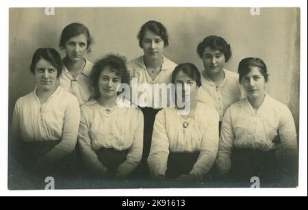 Ritratto originale dell'era del WW1, gruppo di donne piuttosto giovani, tutte di età simile, nei loro anni dell'adolescenza tardivi o nei primi anni venti, abbastanza probabilmente studenti universitari, forse formazione degli insegnanti, probabilmente dalle classi medie. Indossano i loro capelli in su nelle acconciature del bun del chignon, alla nuca, in modo che i capelli sembri corti, uno stile tipico del periodo WW1, ciascuno che porta una variazione sulla moda per una blusa indossata con una gonna lunga - bluse bianche differenti tutte con una spilla. Studio di J.H. Bagley, 44 North St. Ripon, North Yorkshire, Inghilterra, Regno Unito circa 1917-1919. Foto Stock