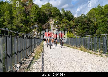 Un gruppo di ciclisti norvegesi di mezza età che attraversano un ponte sulla ferrovia da Spoleto a Norcia in disuso a noleggio. Umbria, Italia. Foto Stock