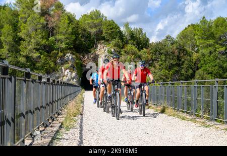 Un gruppo di ciclisti norvegesi di mezza età che attraversano un ponte sulla ferrovia da Spoleto a Norcia in disuso a noleggio. Umbria, Italia. Foto Stock