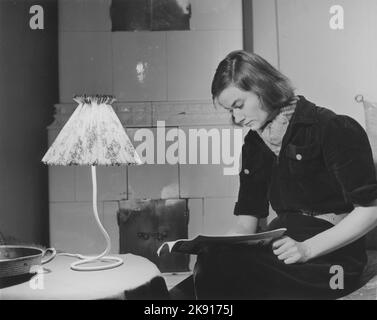 Donna negli anni '1950s. Una giovane donna dai capelli scuri a casa che legge una rivista. Svezia 1950 Foto Stock